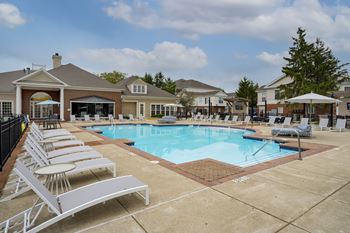 A pool with sun loungers in front of a building.
